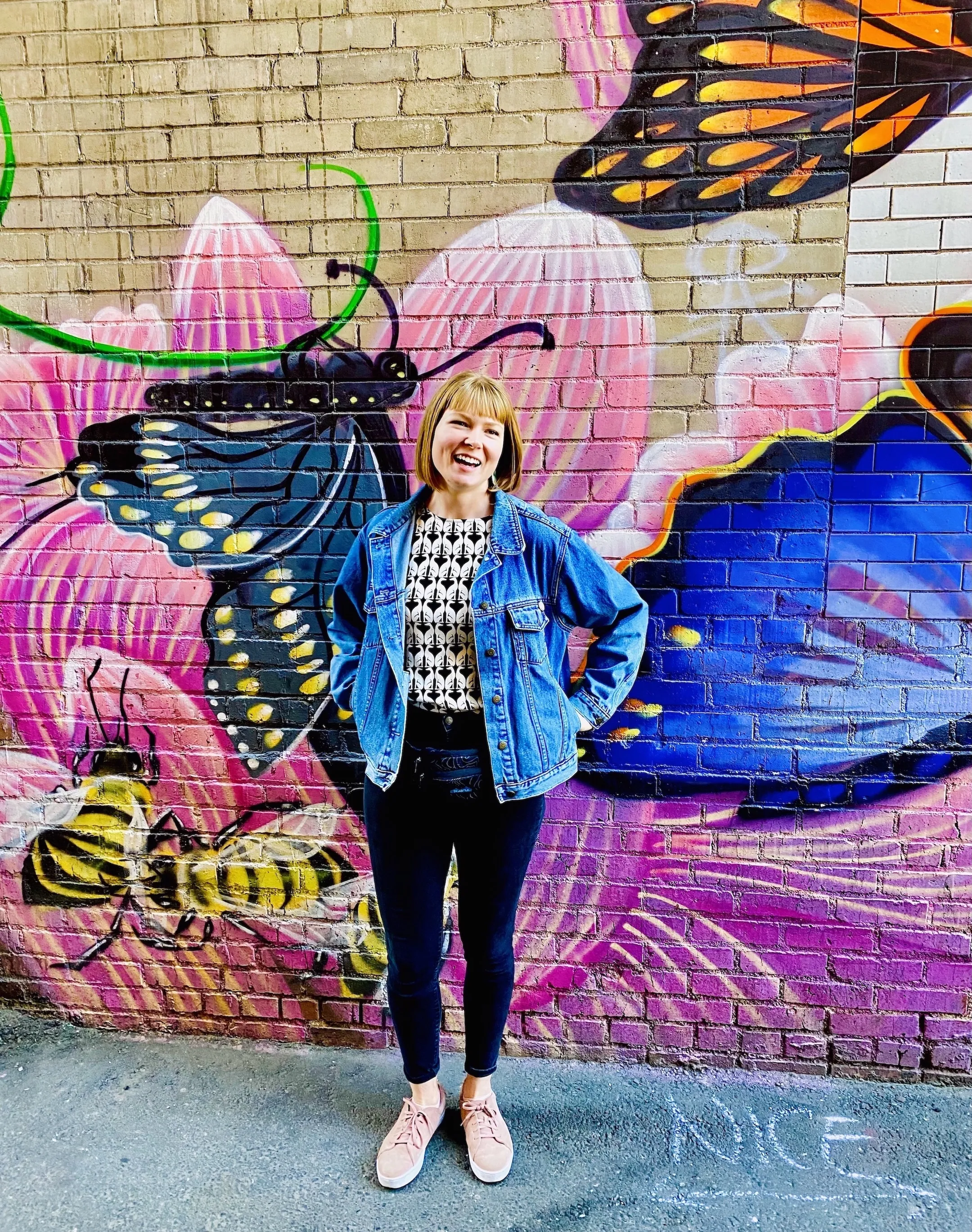 Smiling owner of Vibe Gardens, Charlotte Hadden, in front of butterfly mural backdrop