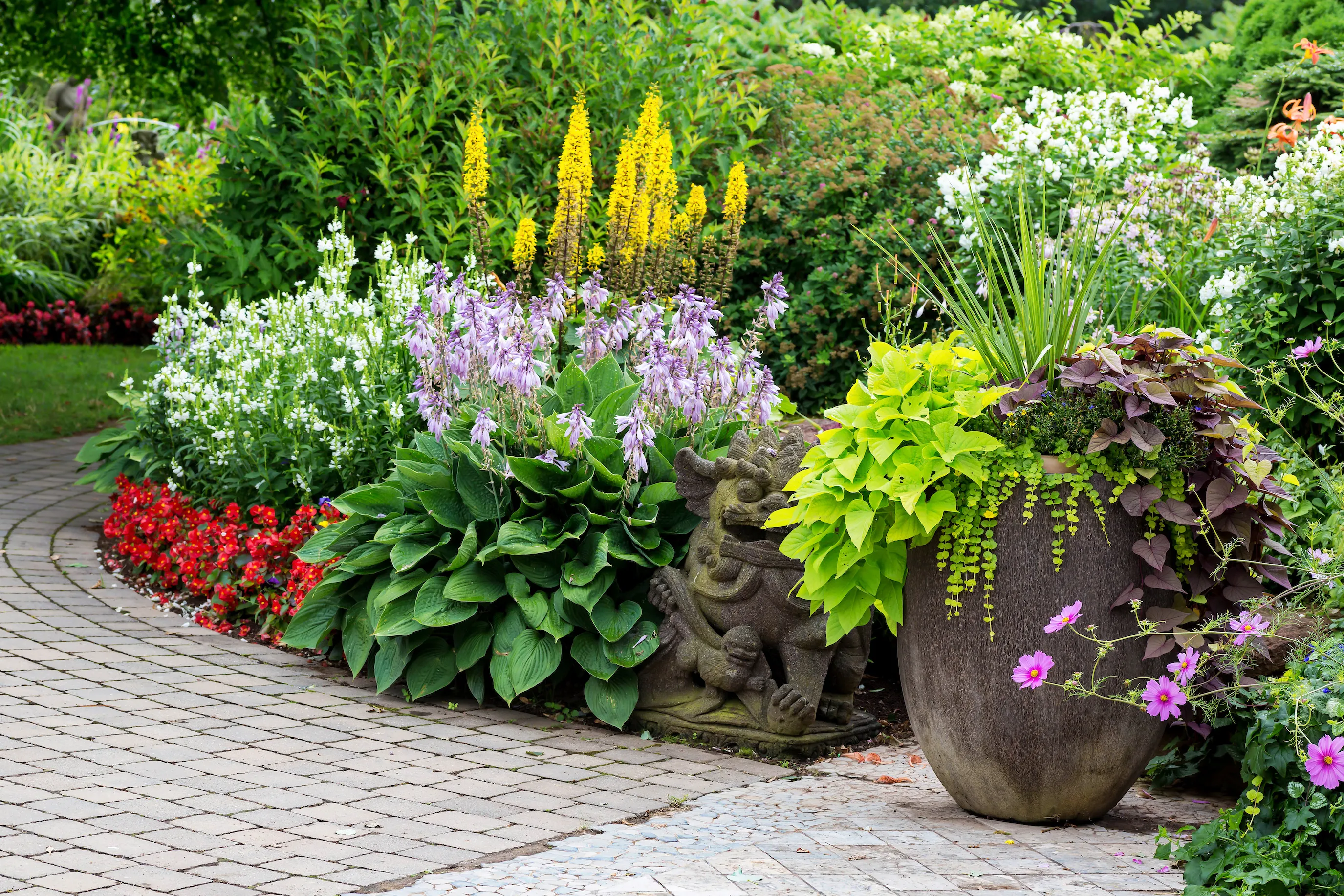 Vibrant garden with hostas and other plants in ornate pots