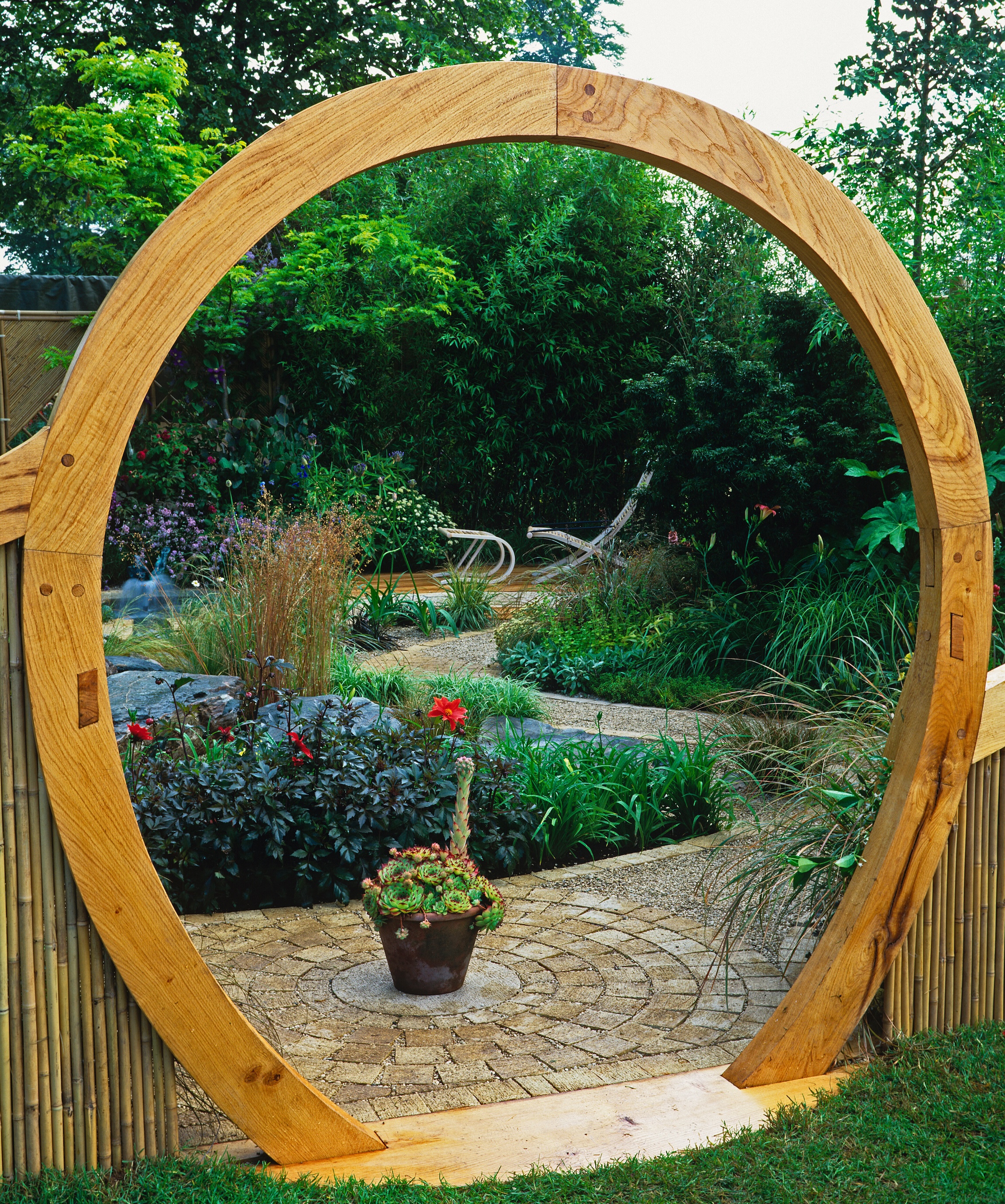 Wooden archway leading to curving path through luscious garden